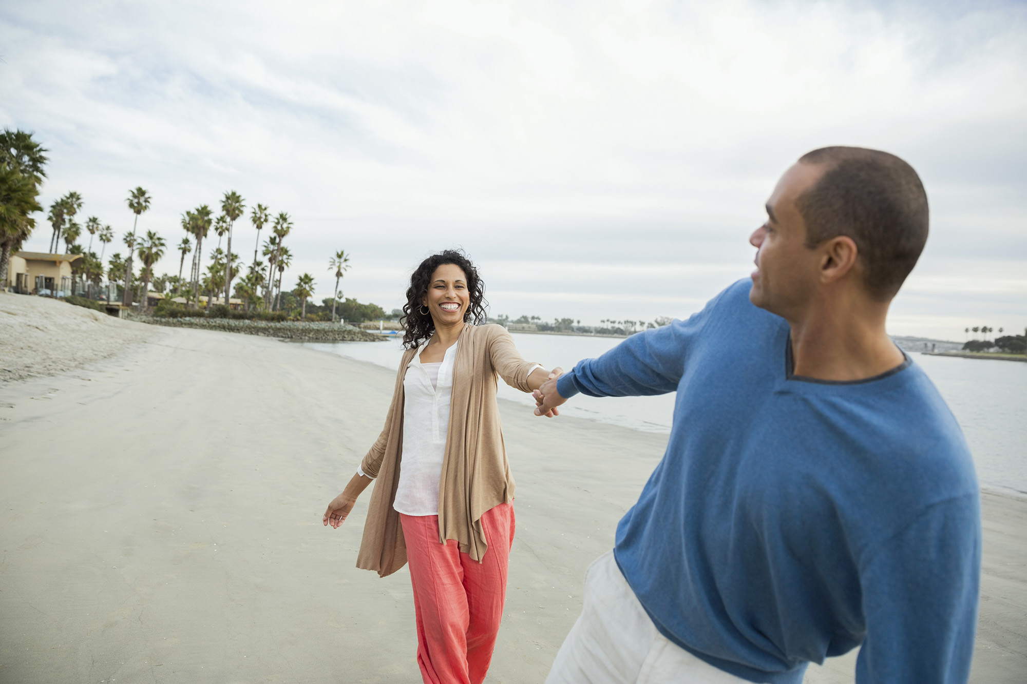 Man holding woman's hand on beach in San Diego